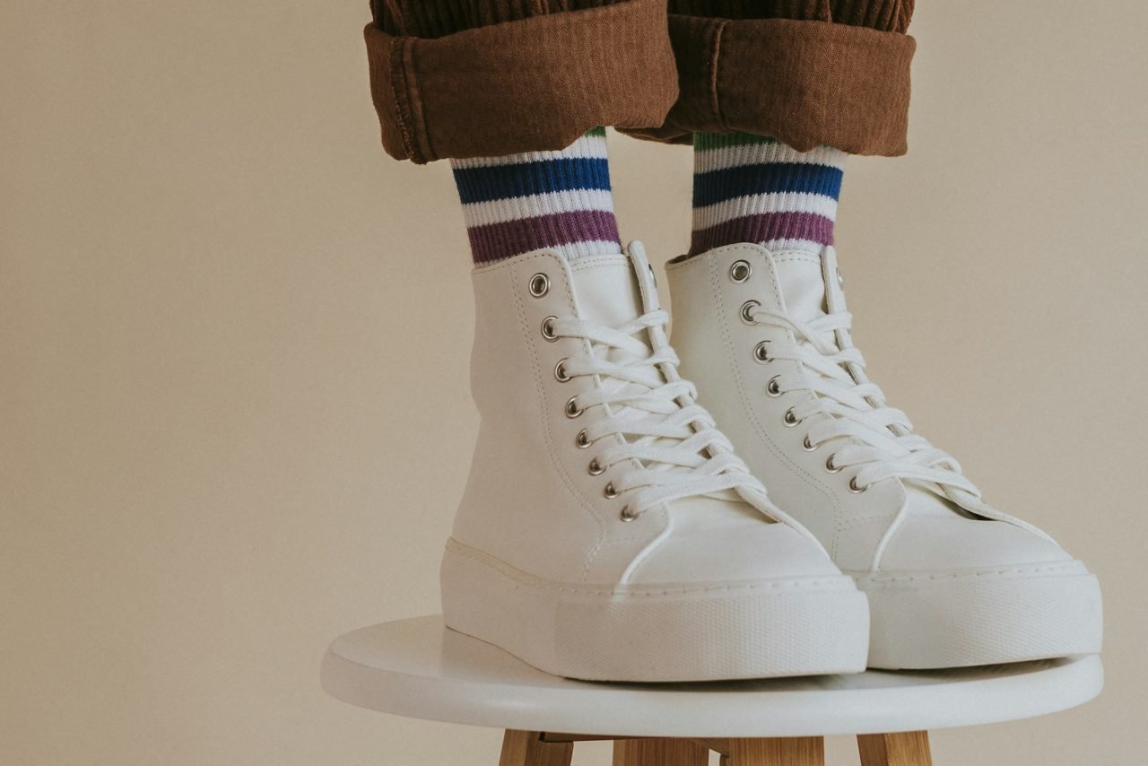 man in white high top shoes standing on chair